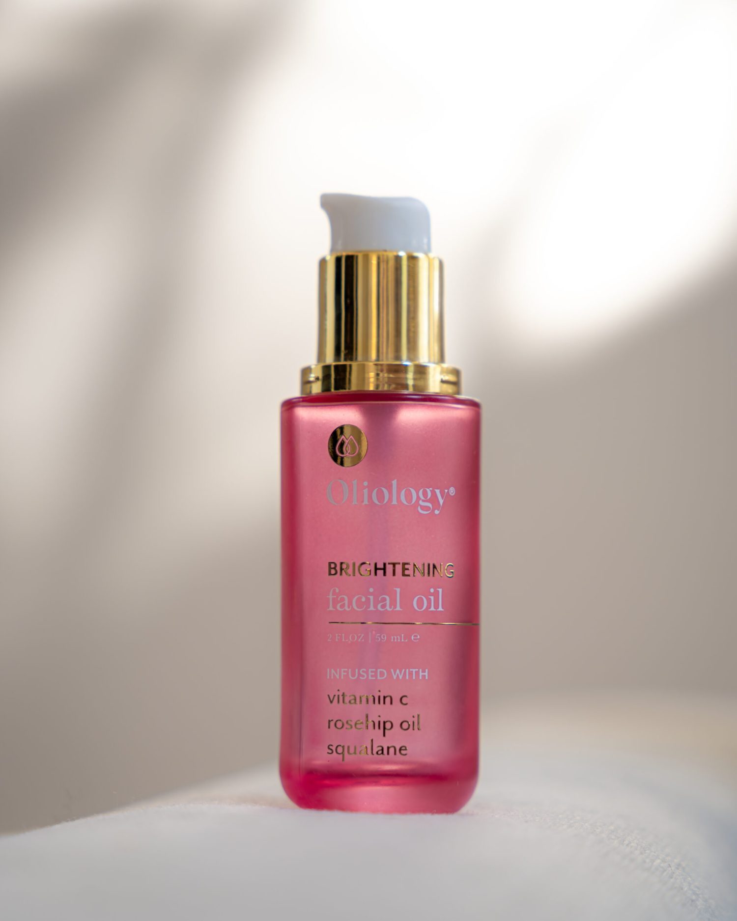 Minuit studio brand photo – Close up on an Oliology serum pump Minuit studio brand photo - Close up on an Oliology serum pump tube with pink and gold tones. photography is made on a white environment and includes play with shadows and lights